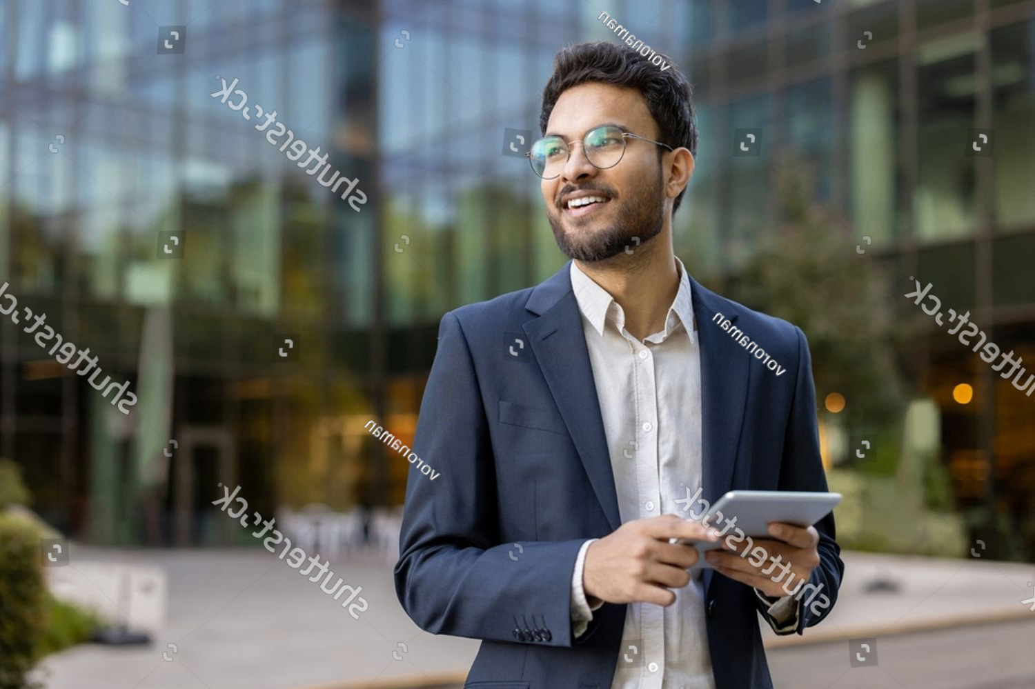 stock-photo-confident-business-man-in-glasses-and-suit-using-tablet-outdoors-with-modern-office-building-in-2492532925_